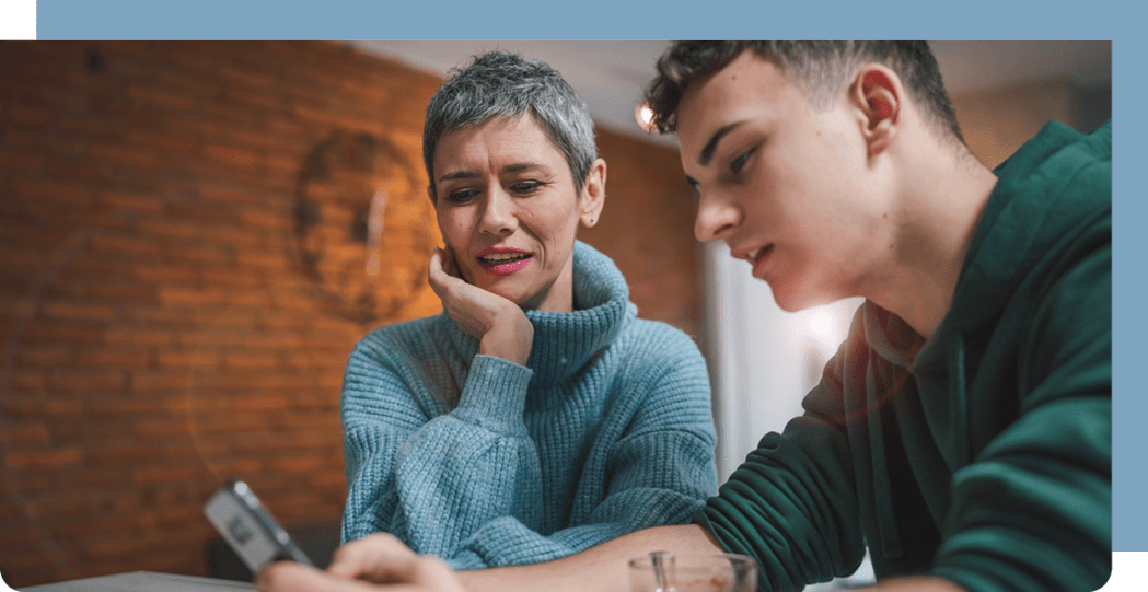 Image of young adult and parent reading a phone screen.