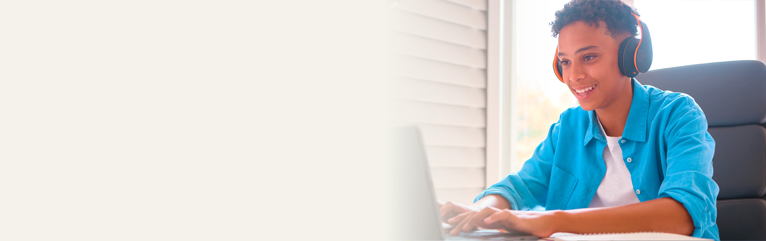 Image of smiling young adult typing on a laptop.
